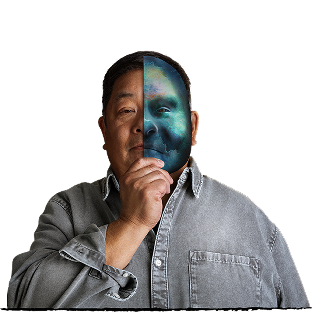 Person wearing a gray shirt holding a half mask on the face against a beige background.